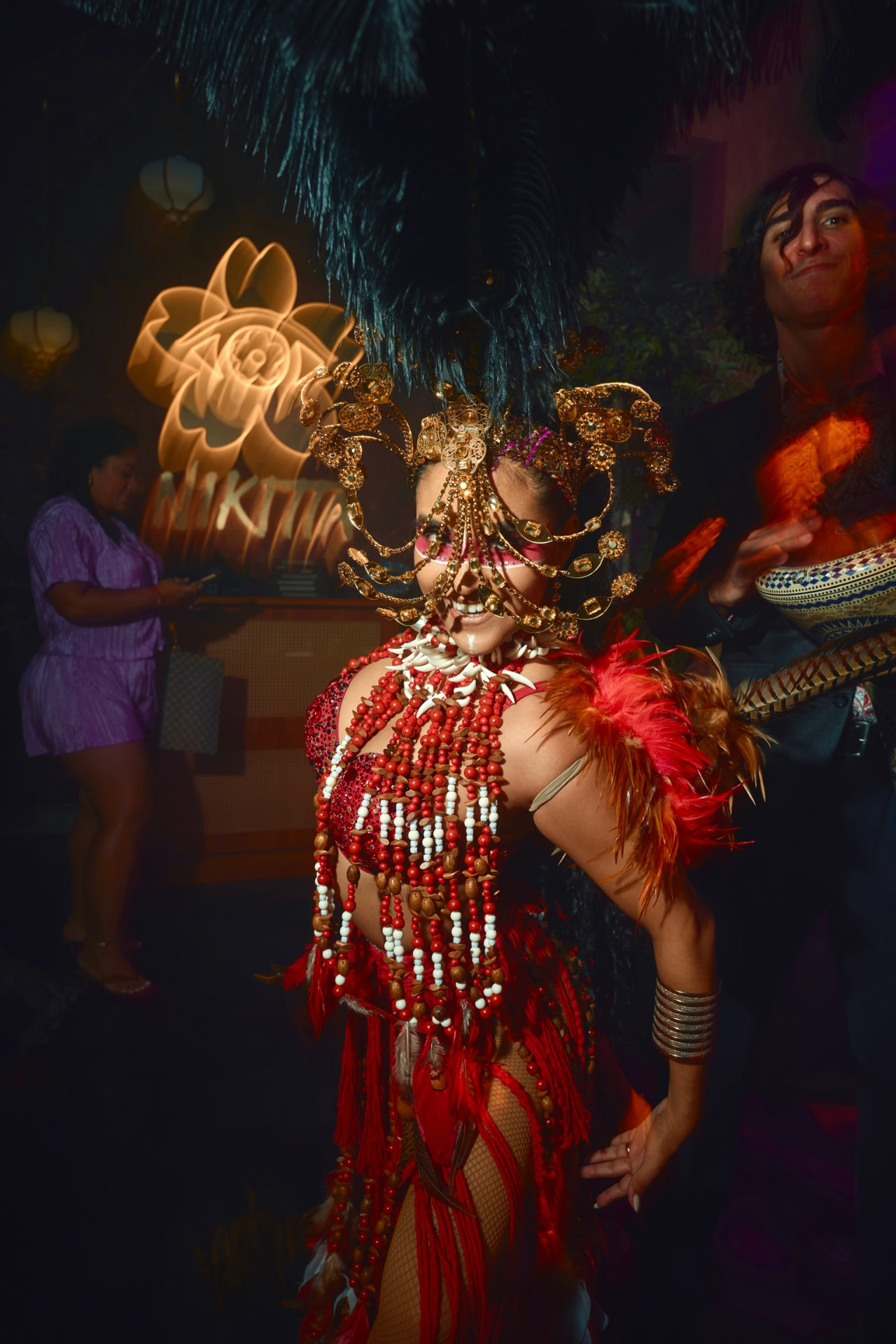 Carnaval performer in a gold headpiece and red feathered costume