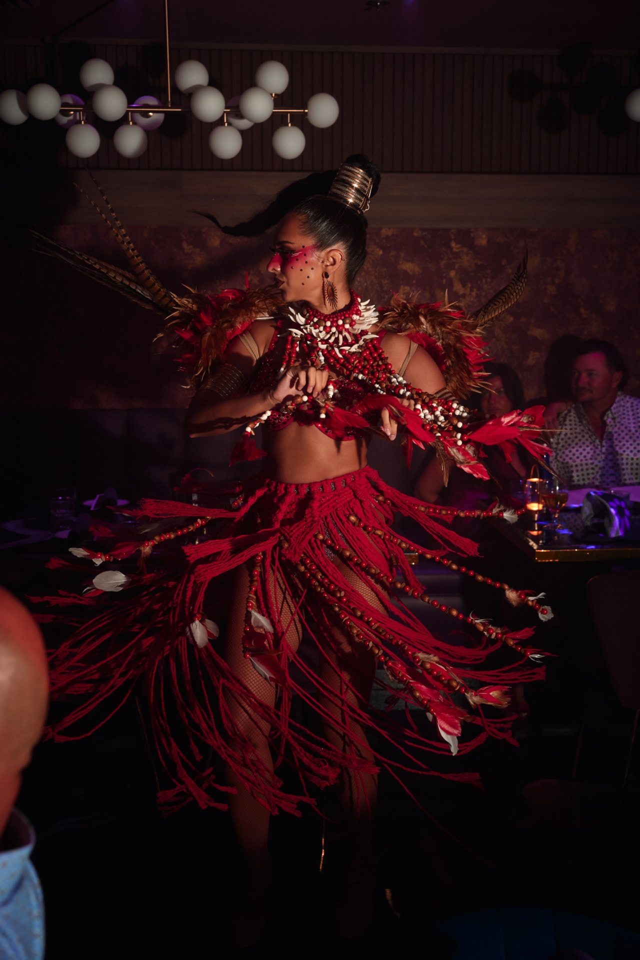 Dancer in a red fringed tribal costume performing between tables